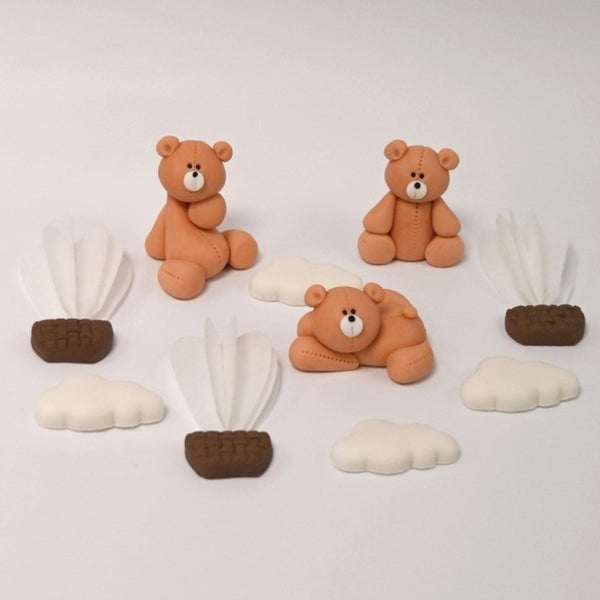 Flat lay of edible cake toppers including fondant teddy bears, white clouds, and hot air balloon decorations.
