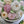 Load image into Gallery viewer, Close-up of a flower bouquet cake with marshmallow roses in white, cream, and soft pink, with green leaves.