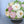 Load image into Gallery viewer, Floral cake arranged like a bouquet with white, cream, and pink marshmallow roses and green leaves in a bowl.