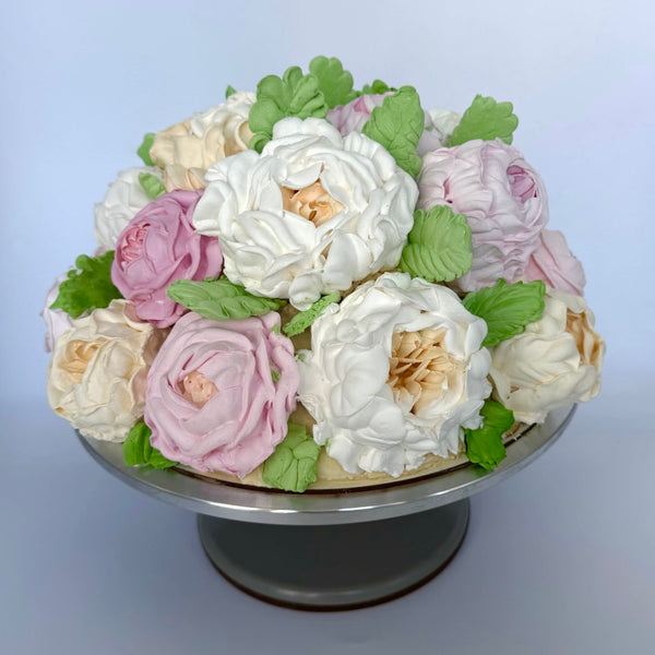 Elegant cake shaped like a bouquet of marshmallow roses in white, blush, and beige tones with leafy detail.