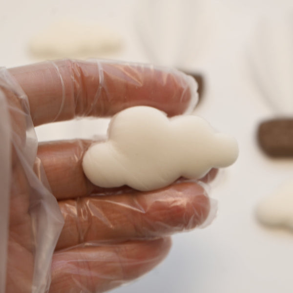 Close-up of a fondant cloud with soft texture, surrounded by hot air balloons and bear cake toppers in the background.