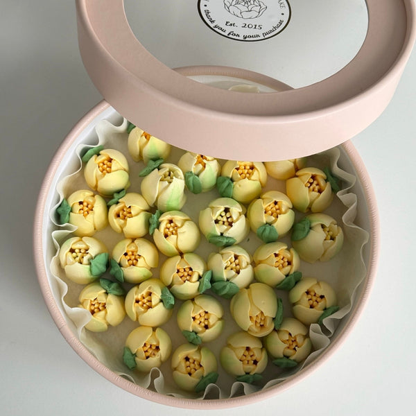 Round gift box with marshmallow flowers on a light gray background.
