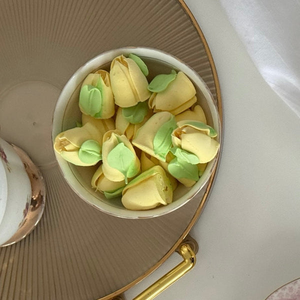 Small white bowl filled with handmade yellow and green  leaf-shaped marshmallow on a decorative plate.