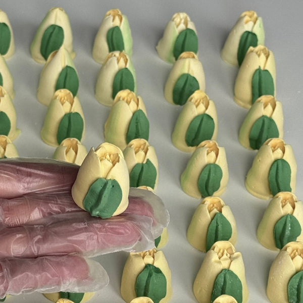 Handmade marshmallow tulip with green leaves on a gray surface.