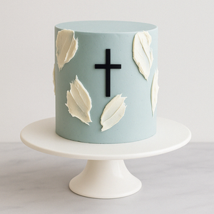 	Blue minimalist cake with white leaves and a black cross, designed for a religious celebration, on a white pedestal.