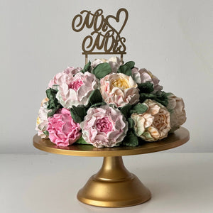 handmade marshmallow flower bouquet cake with pastel flowers on gold cake stand with mr and mrs topper