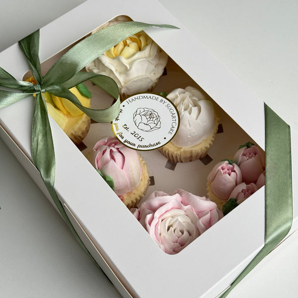 box with cupcakes, decorated with handmade marshmallow tulips, peonies and a green ribbon