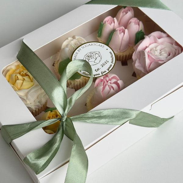 decorative cupcakes in a box with a green ribbon and visible brand logo
