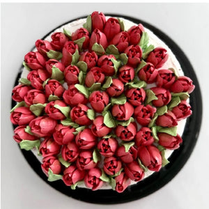 Vibrant red tulip flower cake with dense floral cream decorations, viewed from above.