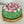 Load image into Gallery viewer, round cake topped with pink marshmallow tulip flowers and green leaves on a gold cake stand
