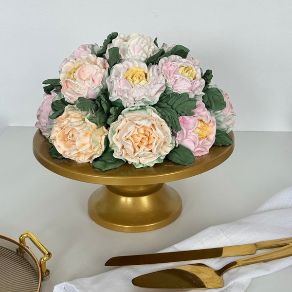 pastel marshmallow flower cake displayed on a gold cake stand with cutlery nearby