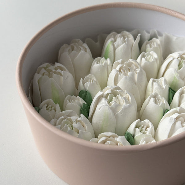 White marshmallow tulips in a pink present box on a light background