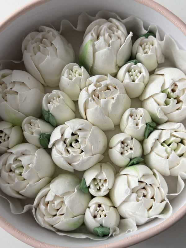 Decorative white flowers arranged in a bowl on a light background
