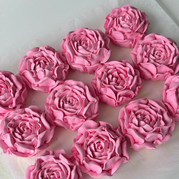 edible pink marshmallow peony toppers arranged on parchment paper
