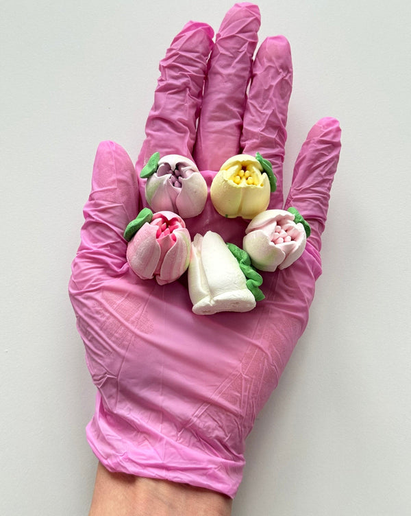 Edible marshmallow tulip flowers held in a pink glove on a white background