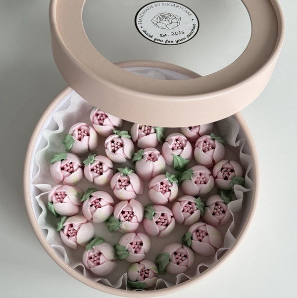 Pink gift box with marshmallow flowers and visible brand logo on a light background