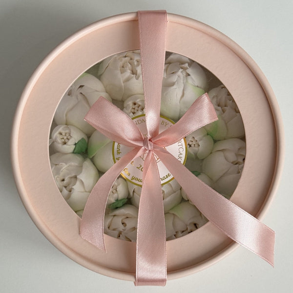 Round gift box with pink ribbon and white tulips on a light gray background