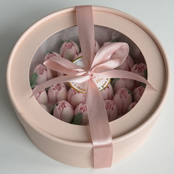 Gift box with a pink ribbon containing pink flowers decoration on a light gray background