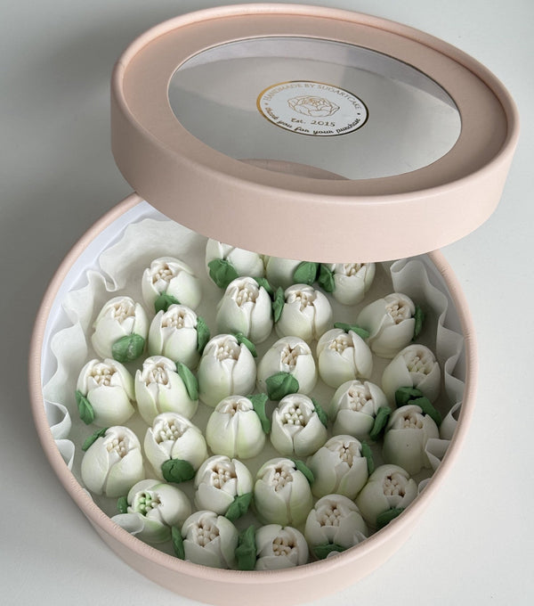 Round pink box filled with edible white marshmallow tulip flowers on a light background